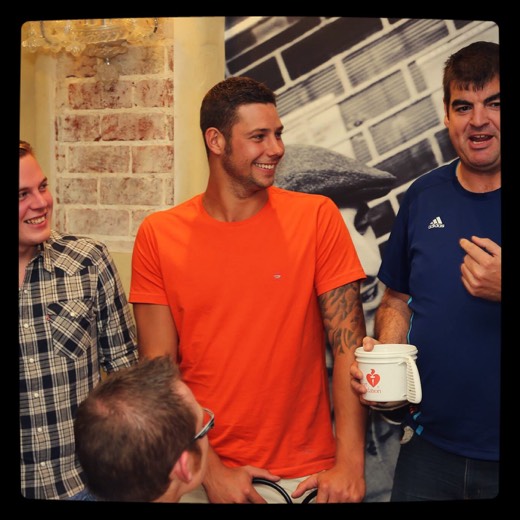 A closer crop of Gary holding a Heart Foundation collection tin with supporters beside him at Catalano's