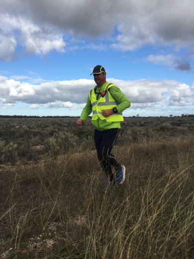 Gary in hi-vis walking gear moving through roadside grass on the Eyre Highway east of Cocklebiddy