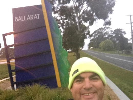 Gary in the yellow beanie beside the Ballarat sign after restarting from Ballarat on Day 80