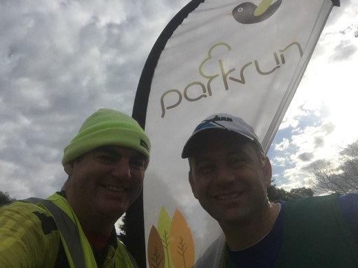 Gary beside the Bowral parkrun flag with Bowral parkrun Event Director Barry on Day 99.